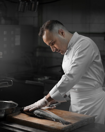 A chef preparing fish on a wooden cutting board.