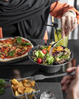 People eating pizza, salad, and fries at a table