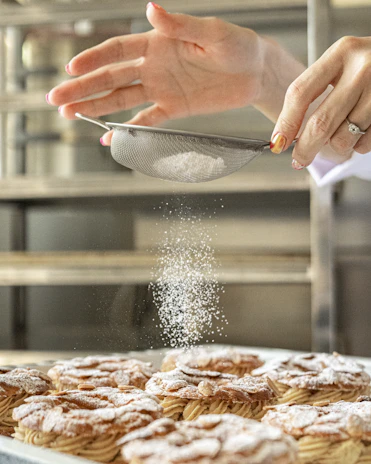 A baker's hands carefully decorating a cake with colorful icing in a cozy bakery kitchen.