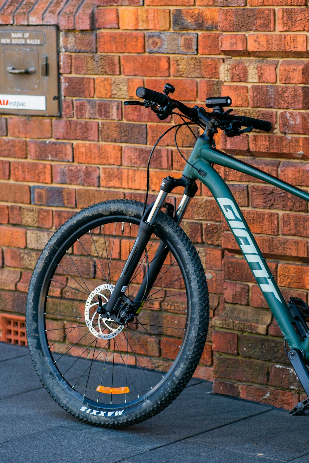 blue and black mountain bike leaning on brown brick wall