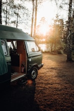 A cozy van parked in a forest clearing at sunset, with warm light glowing inside.