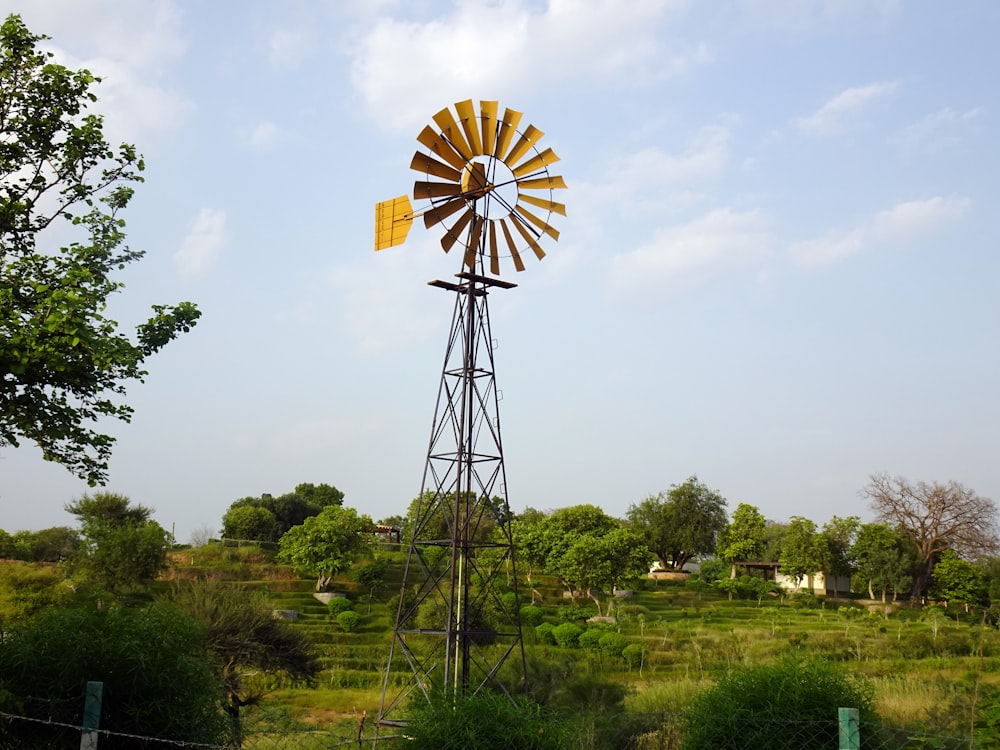 Moulin à vent jaune et rouge sur un champ d’herbe verte sous des nuages blancs et un ciel bleu pendant la journée