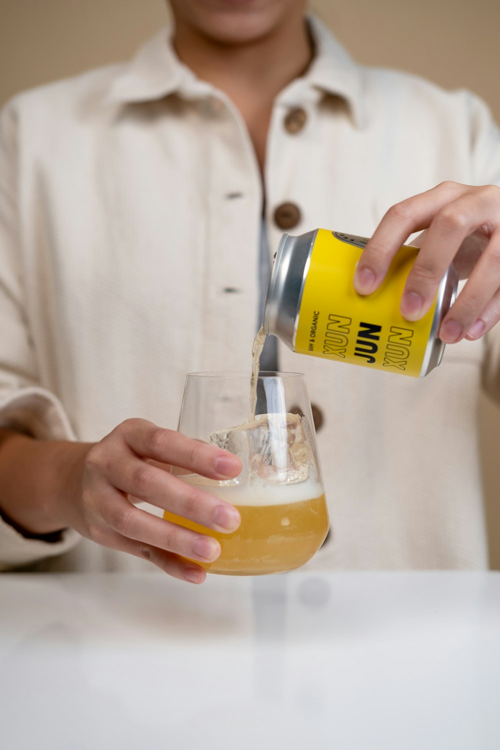 person pouring yellow liquid on clear drinking glass