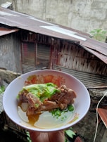 A handwritten recipe book open beside a bowl of homemade soup.
