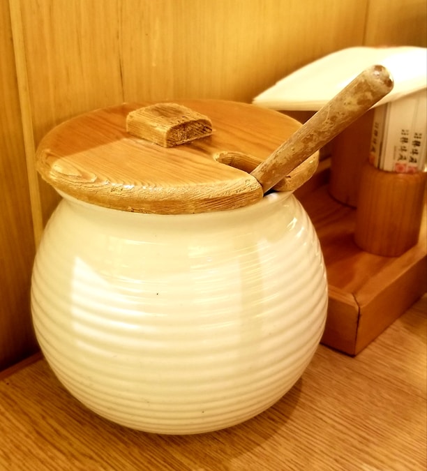 Golden jar of ghee with a wooden spoon on rustic wooden table