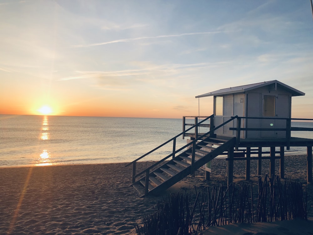 white wooden house on sea shore during sunset