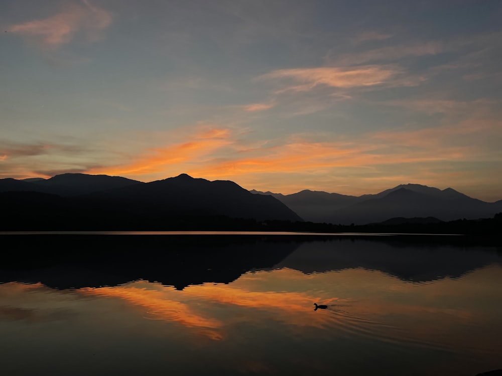 body of water near mountain during sunset