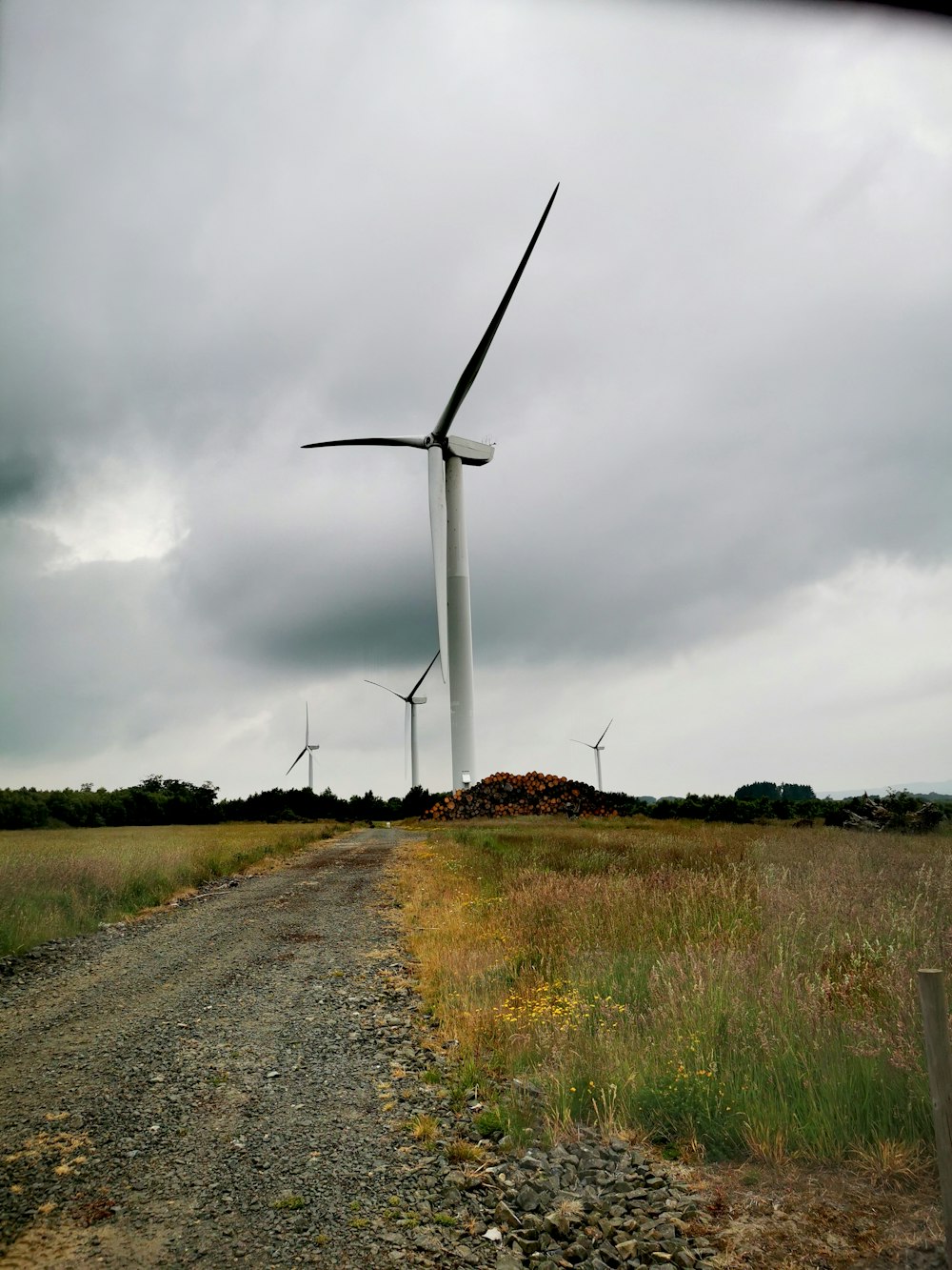 white wind turbine on green grass field under gray cloudy sky