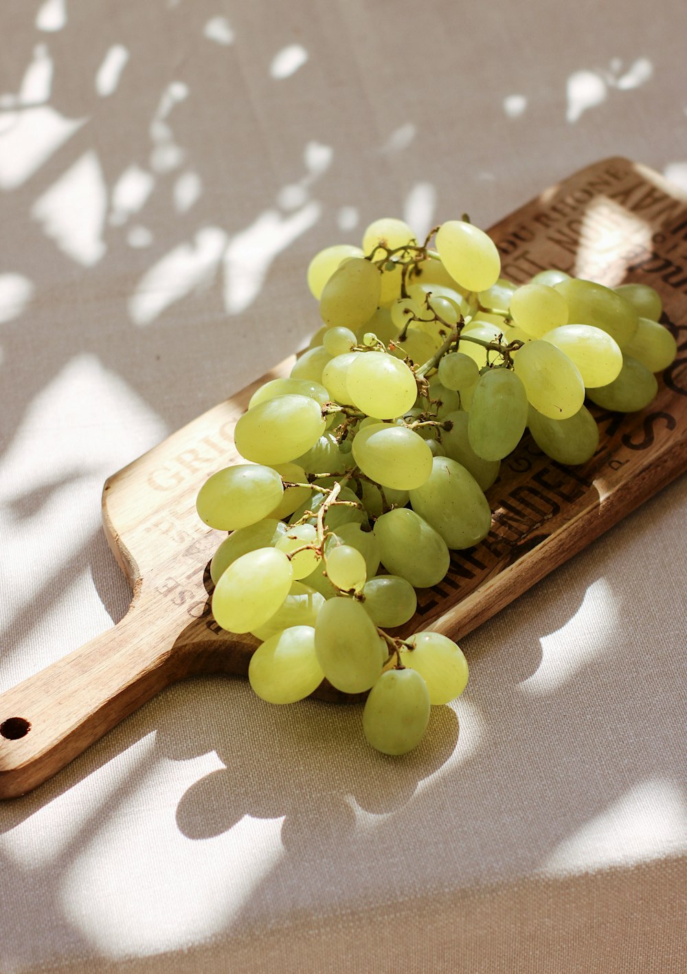 uvas verdes en tabla de cortar de madera marrón