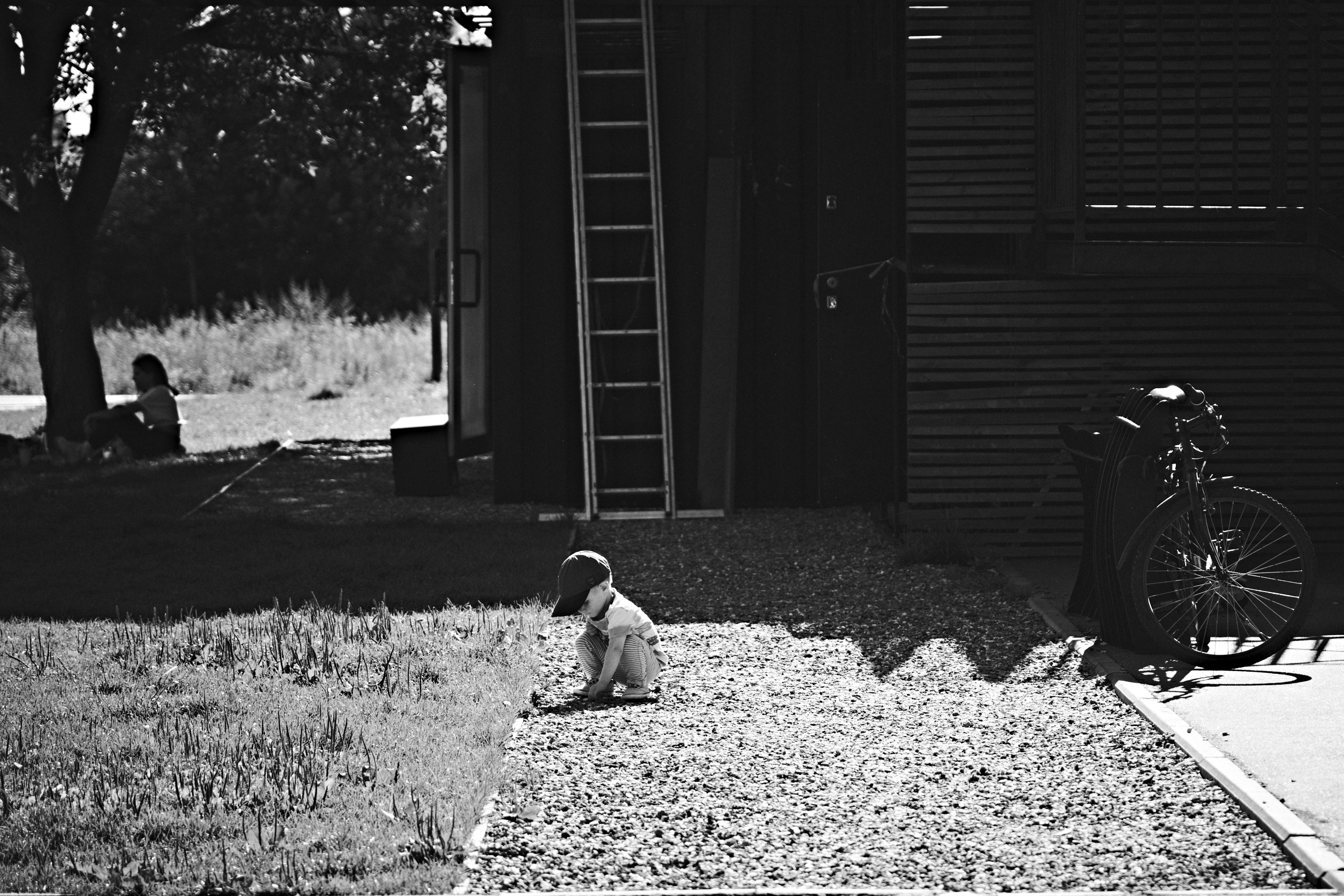 A black and white photo showing a grieving family, with a child crying, in front of a small, humble house, implying the loss of a loved one.