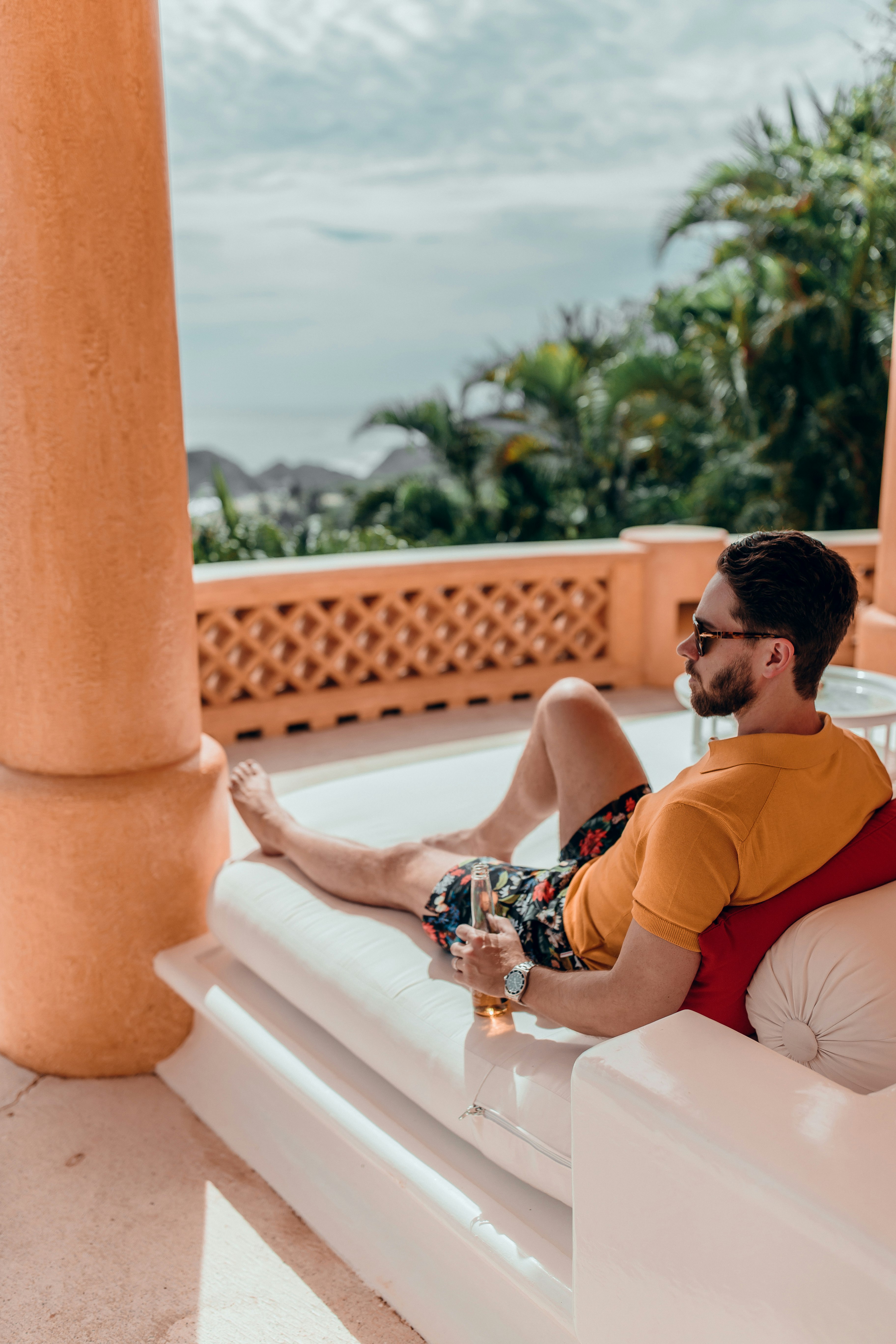 man in orange t-shirt sitting on white concrete bench during daytime