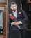 man in black suit holding red rose bouquet