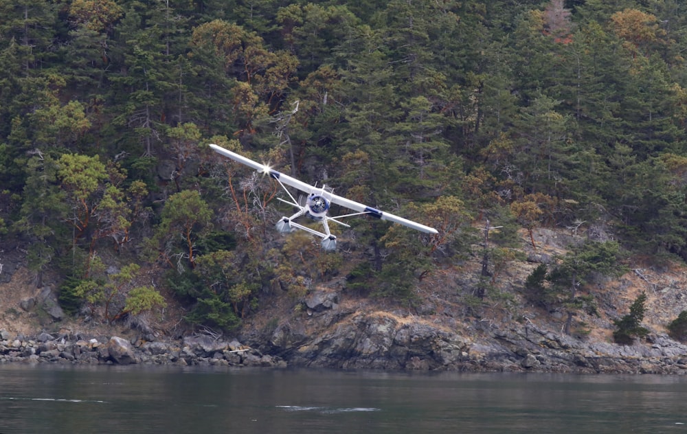 white and black airplane flying over the river during daytime