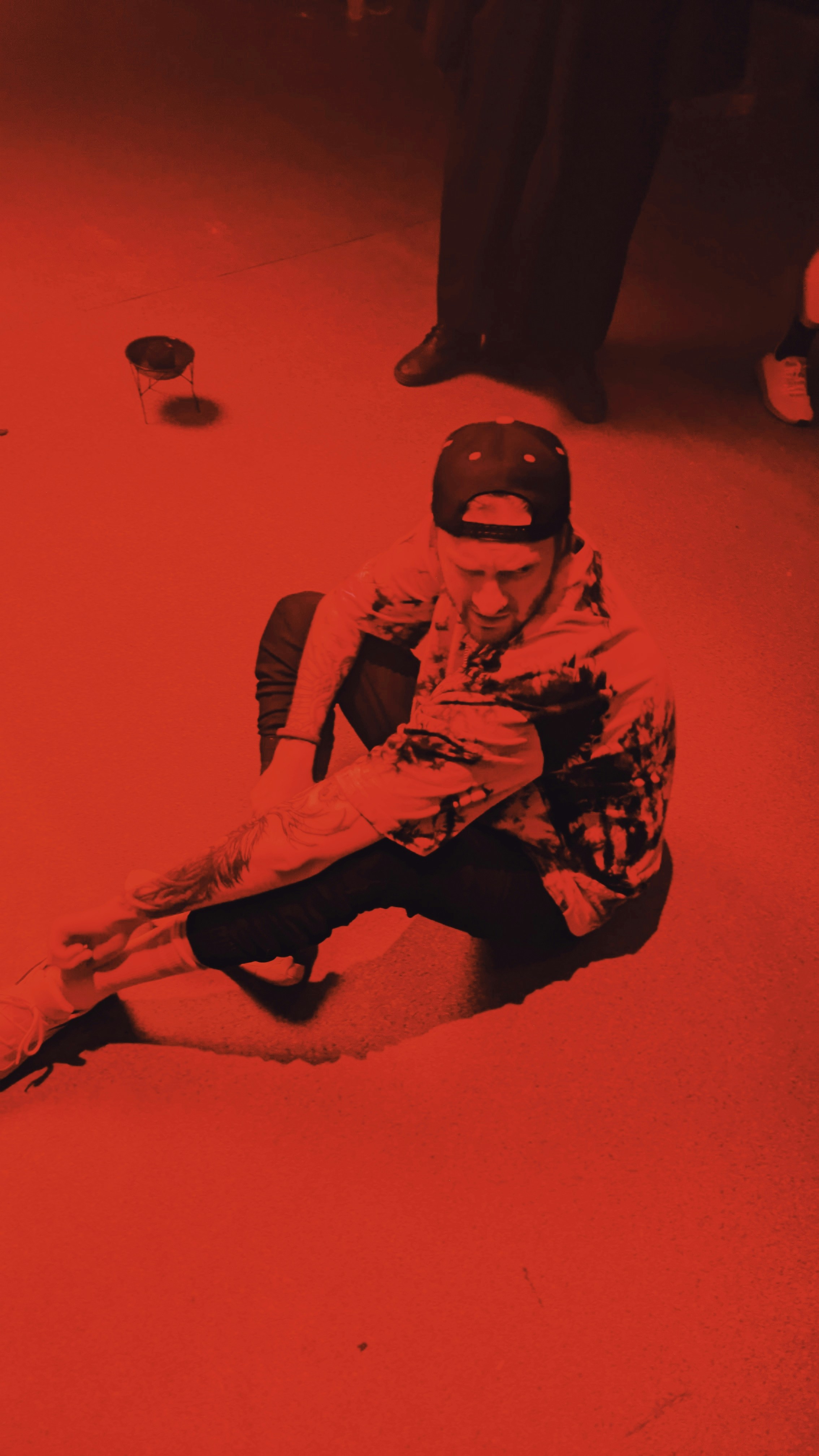 man in black and white camouflage jacket and black pants sitting on floor