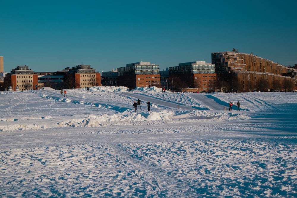 people walking on snow covered field near city buildings during daytime