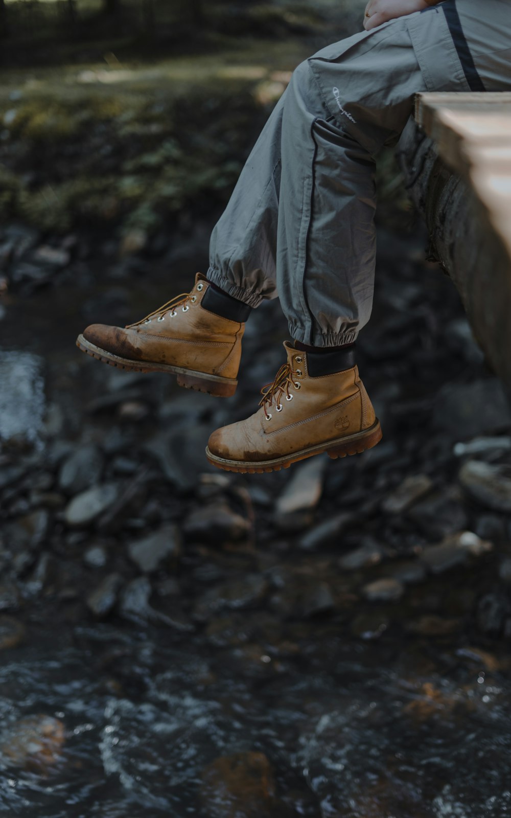 person in black leather jacket and brown leather boots standing on rocky ground