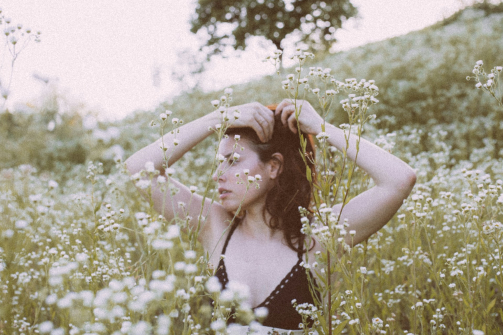 woman in blue and white floral spaghetti strap top standing on green grass field during daytime