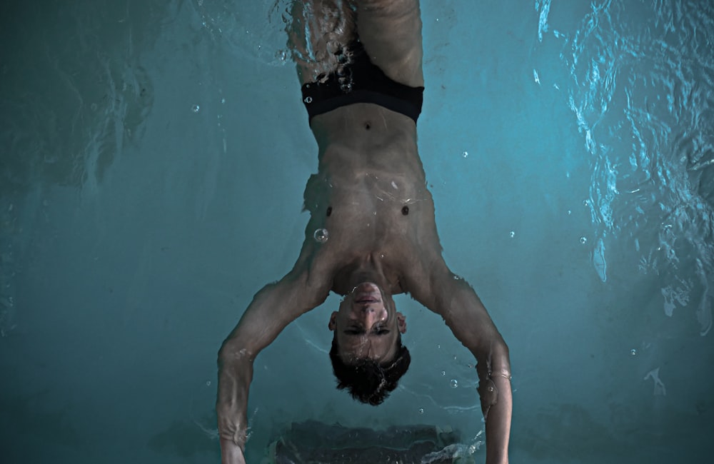 man in black shorts swimming in pool