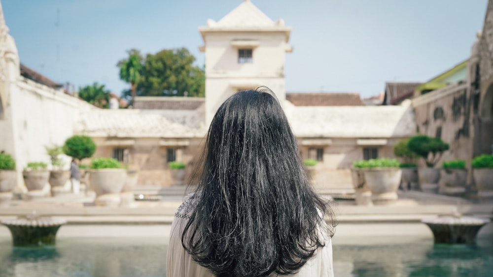 woman in white shirt standing near white concrete building during daytime