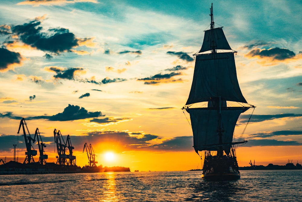 夕暮れ時の海上の帆船のシルエット