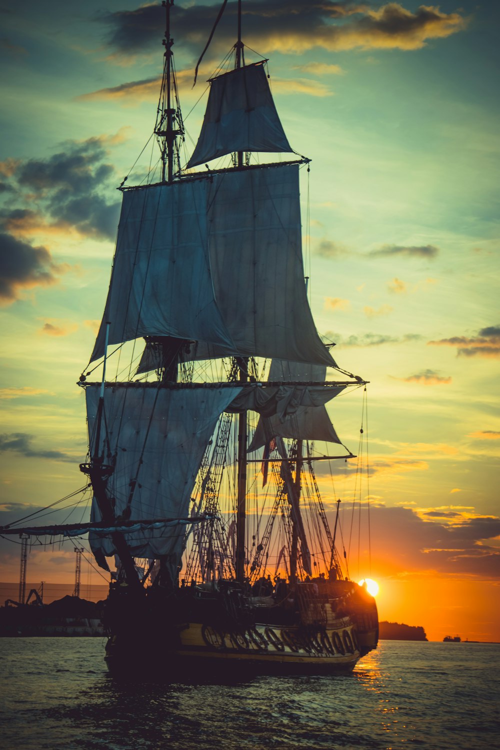 夕暮れ時の海に浮かぶ茶色の帆船