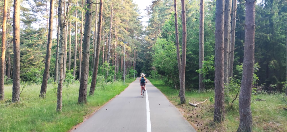 person in red jacket riding bicycle on gray asphalt road during daytime