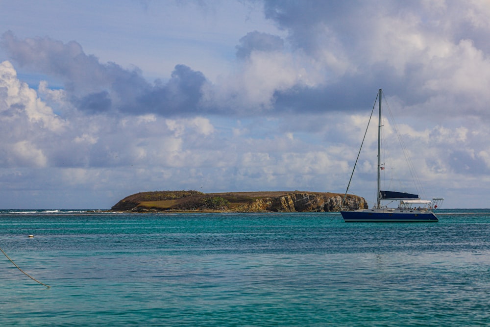 white sailboat on sea under white clouds and blue sky during daytime