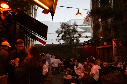 Cozy outdoor seating at a popular local bar filled with laughter and lights.