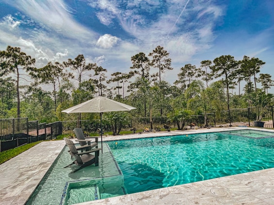 A serene backyard with a pool and lounge chairs under a clear blue sky.