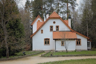 white and brown concrete house surrounded by green trees during daytime