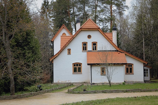 white and brown concrete house surrounded by green trees during daytime