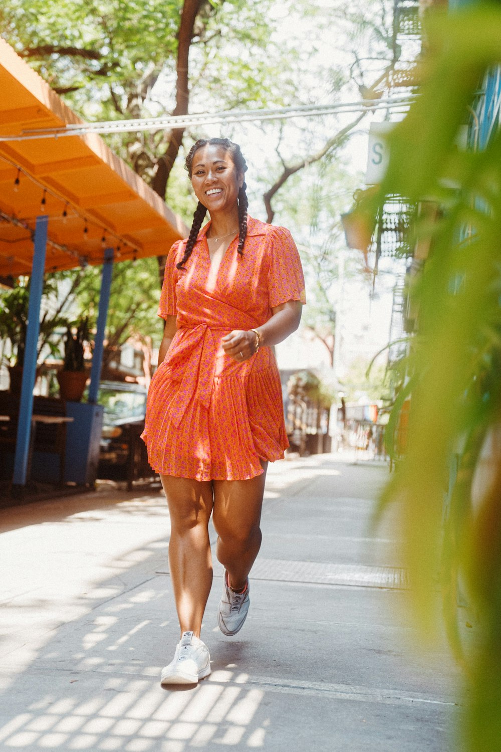 woman in red dress standing on sidewalk during daytime