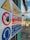 A close-up of a safety sign with warnings and instructions, including 'Limite di sicurezza' and 'Vietato l'accesso ai non addetti'. The sign features symbols such as a hand indicating 'no access' and an icon of headphones with a message about hearing protection. The background shows an outdoor industrial setting.