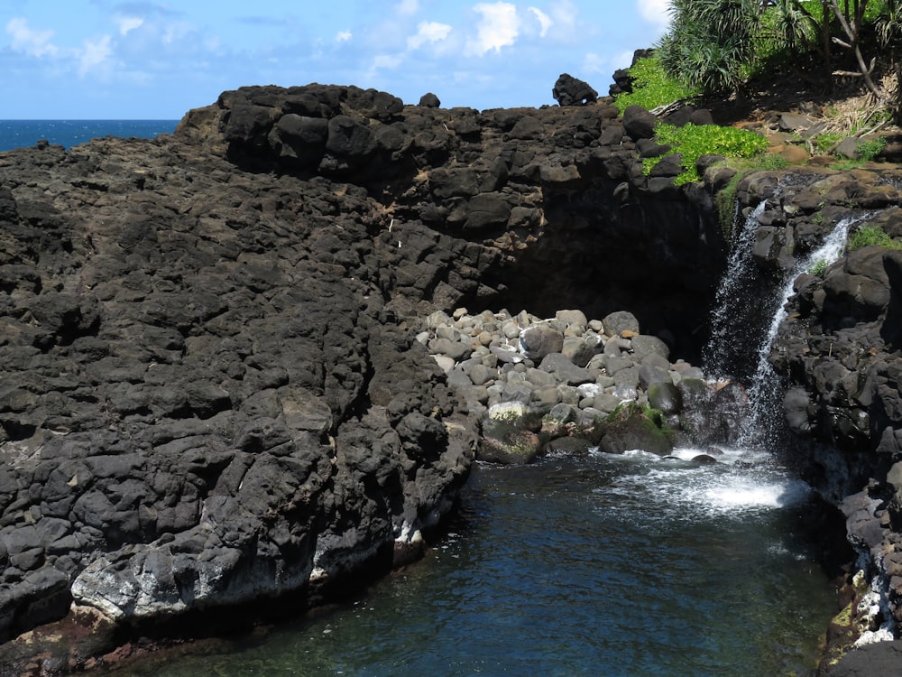 water falls on rocky shore during daytime