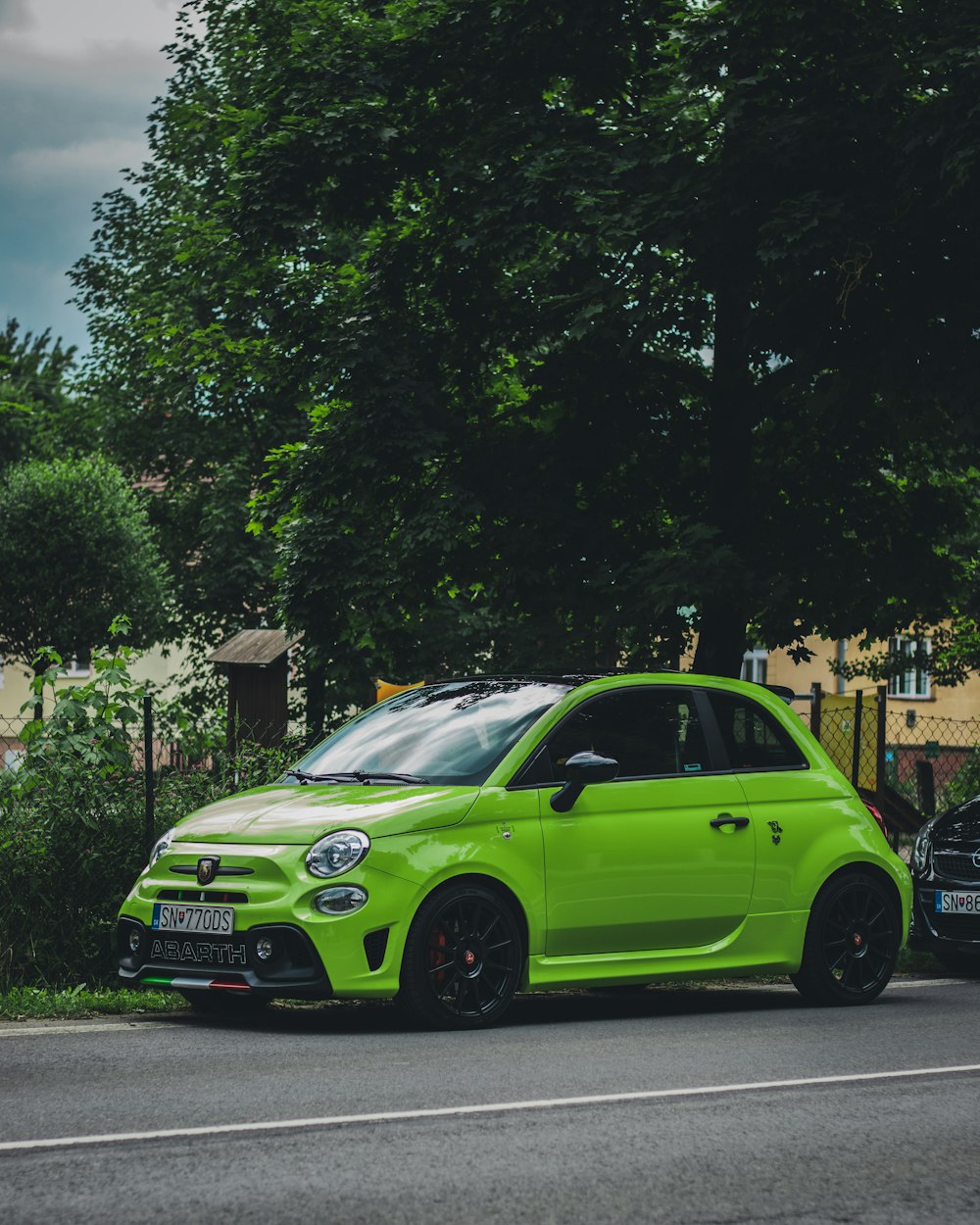 Volkswagen New Beetle verde parcheggiato sul marciapiede durante il giorno