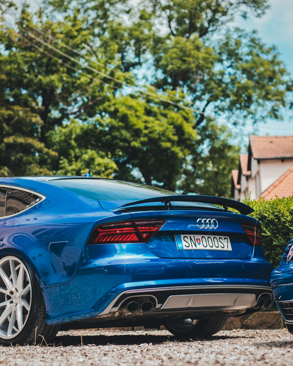 Porsche 911 bleue et rouge garée près de Green Grass pendant la journée