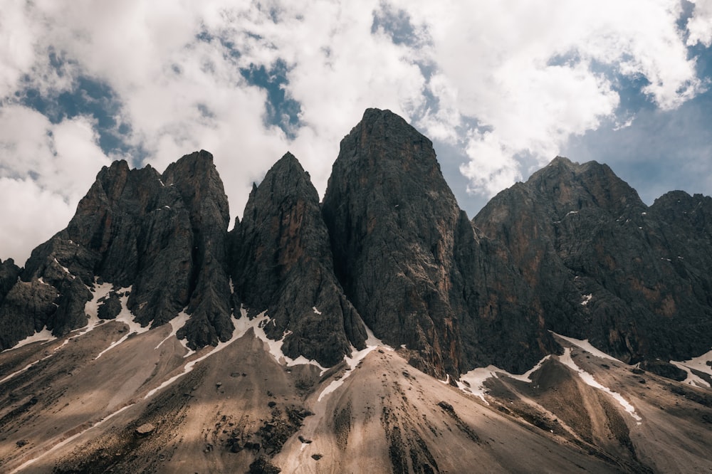 brown rocky mountain under white clouds during daytime