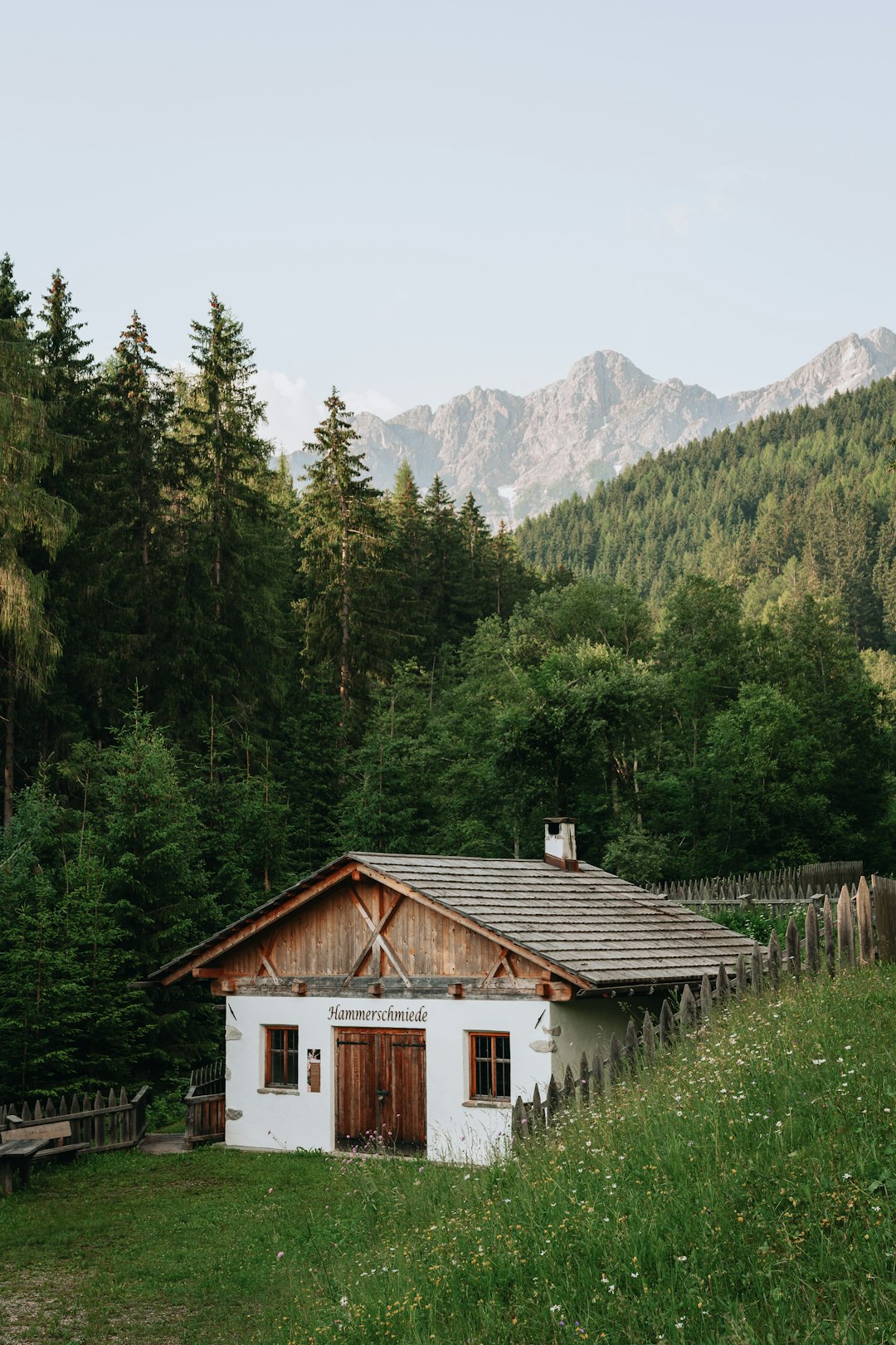 white and brown wooden house near green trees and mountain during daytime