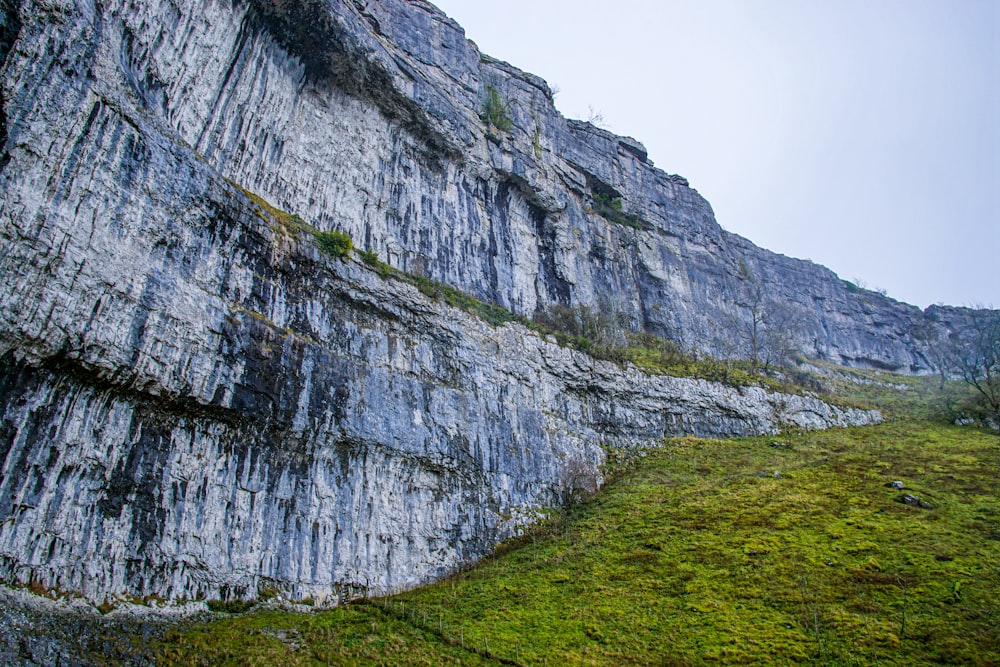 green grass field near gray rock mountain during daytime