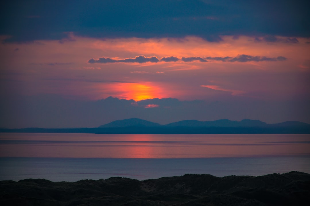 body of water near mountain during sunset