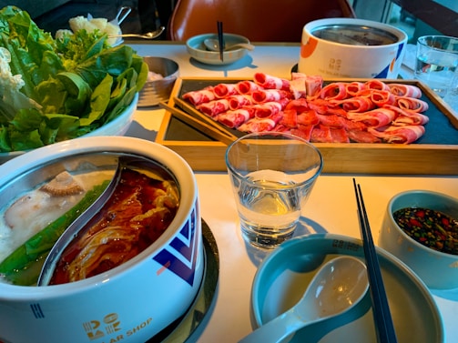 A cozy dining table set with dim lighting, chopsticks, and a shared hot pot bubbling with rich broth.