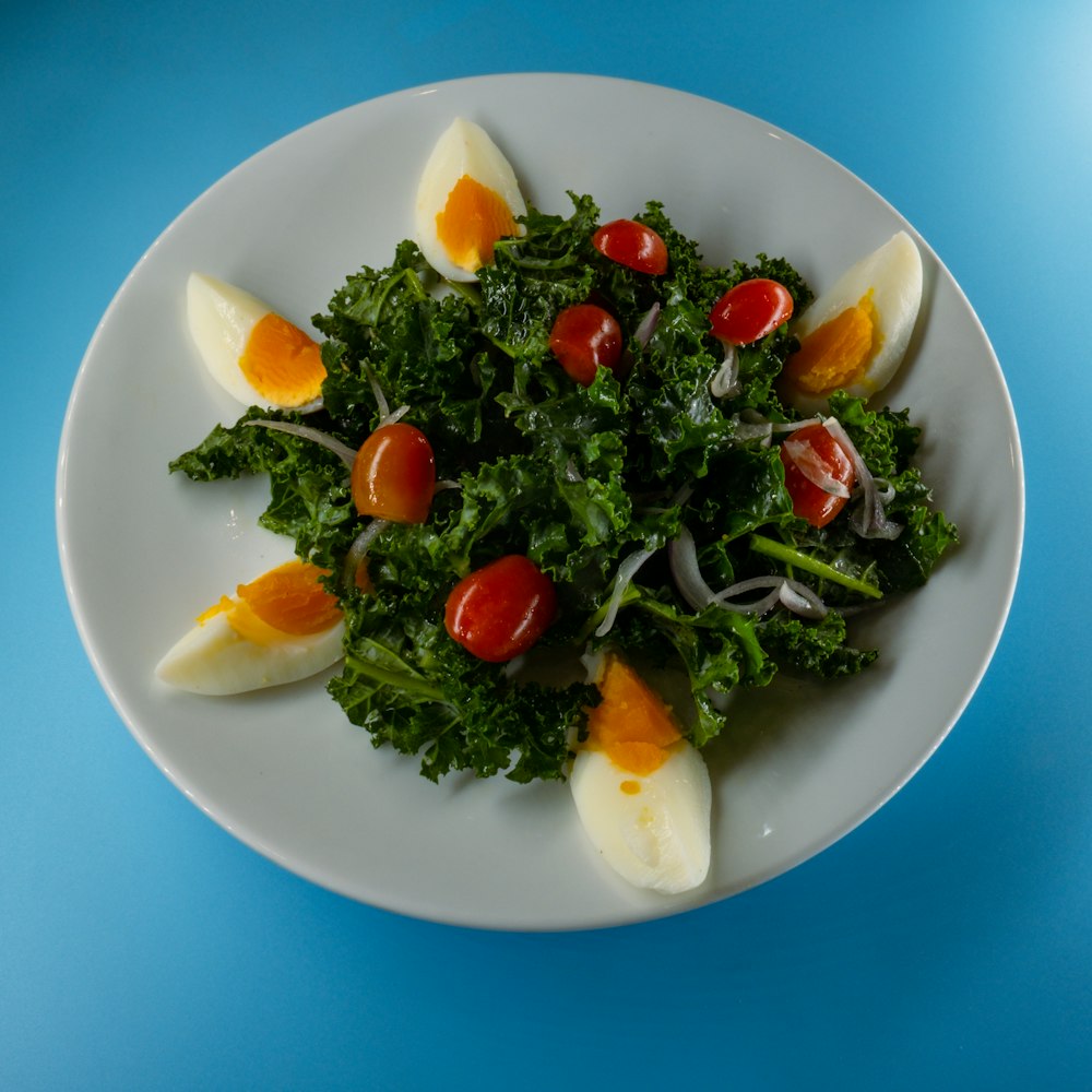 sliced tomato and green leaf vegetable on white ceramic plate