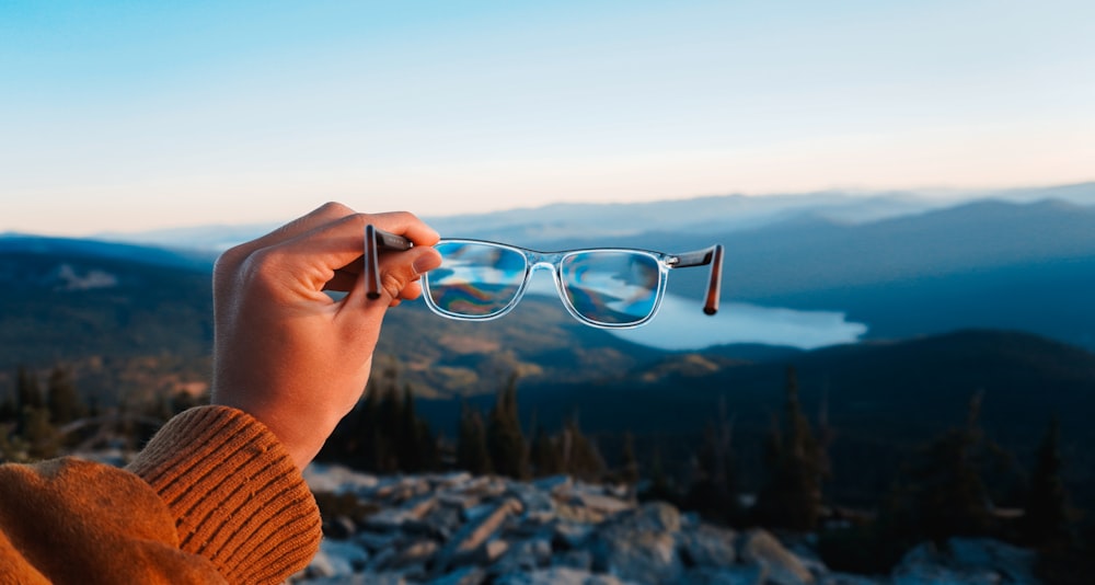 person holding silver framed eyeglasses