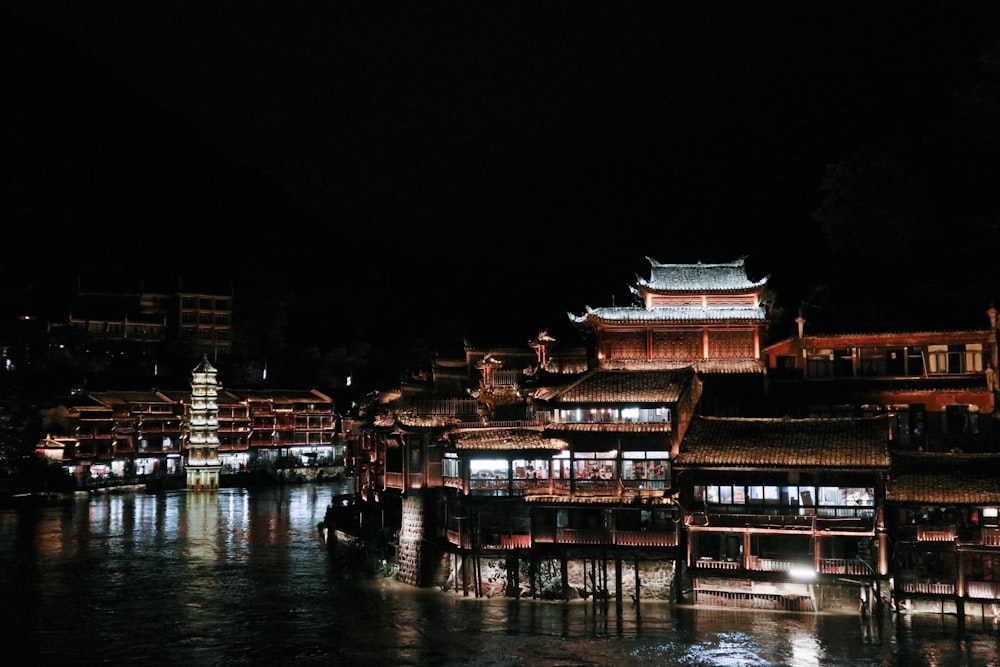 brown wooden building on body of water during nighttime