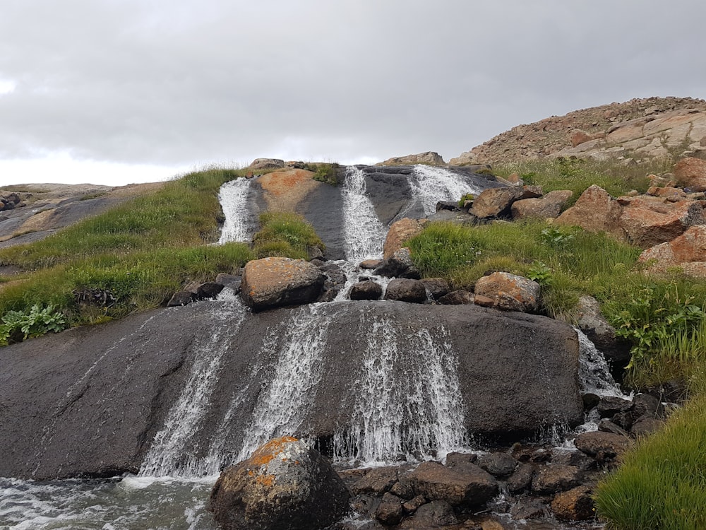 waterfalls on green grass field during daytime