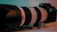 A professional Canon camera with a large telephoto lens is placed on a surface. The lighting is a mix of teal and warm tones, highlighting the lens and camera body. The surface appears smooth and the background is softly blurred, adding focus to the camera setup.