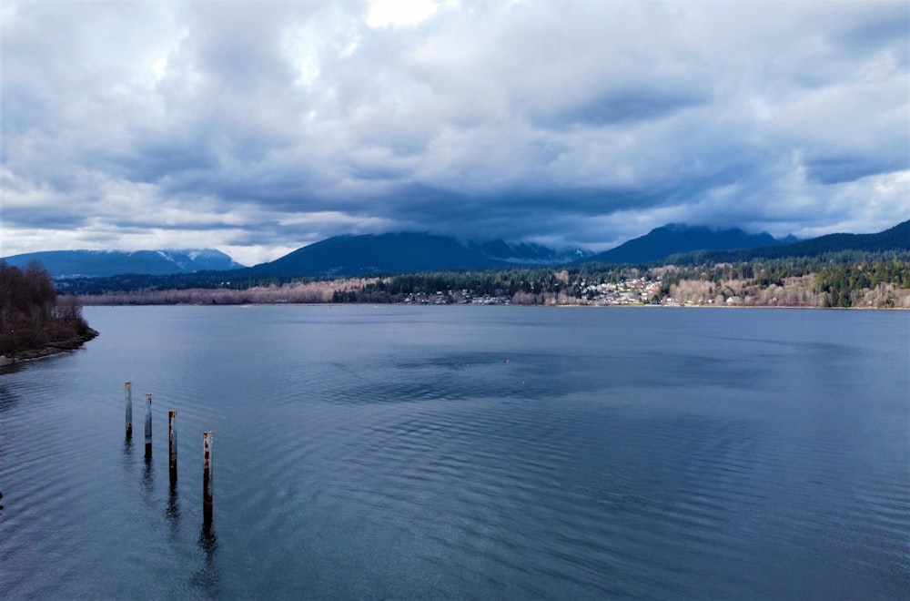 body of water near mountain under white clouds during daytime