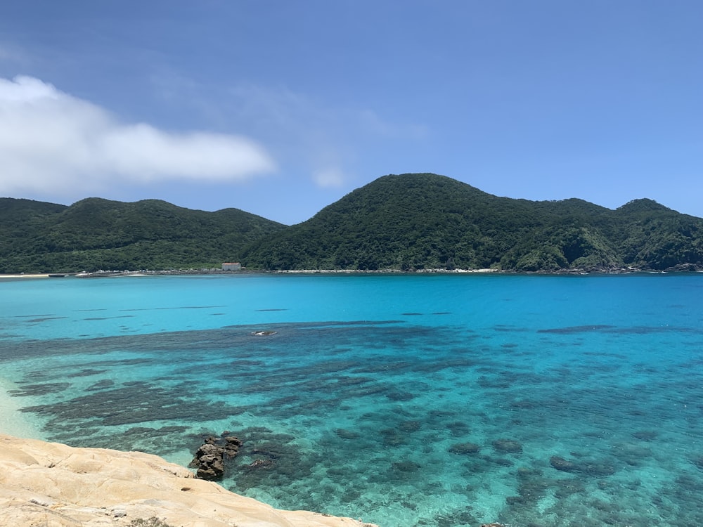 body of water near mountain during daytime