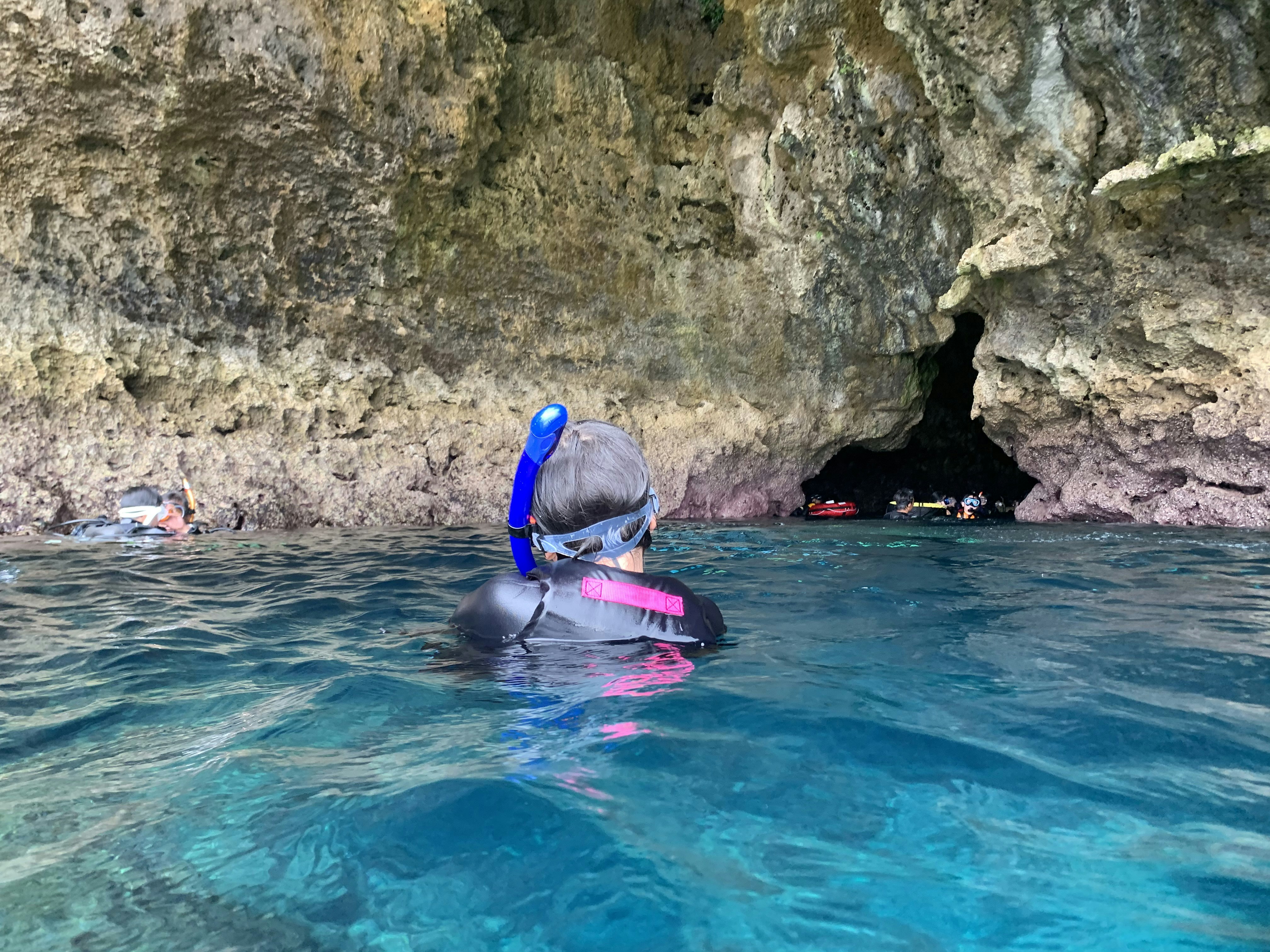 man in blue swimming goggles in blue water during daytime, Child snorkeling at the Blue Cave in Onna, Okinawa, Japan
