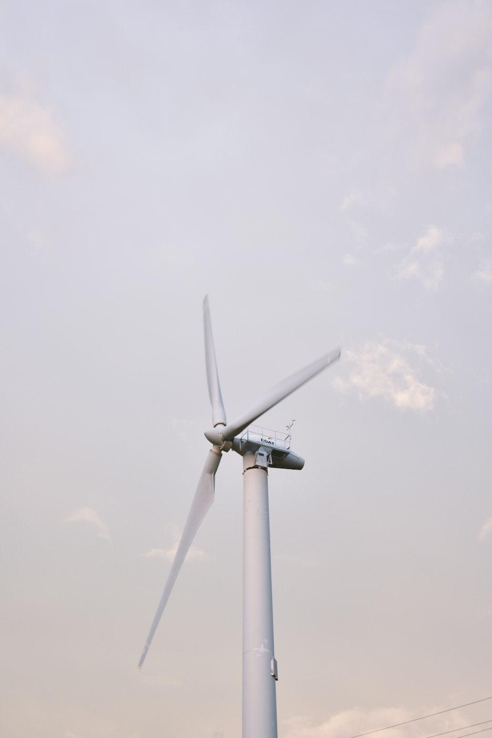 white wind turbine under white sky during daytime